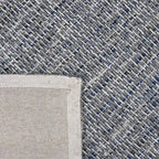Achterkant hoek aanzicht van het vloerkleed HUXLEY in de kleur Denim Blauw, gemaakt van Wol en Viscose mix.