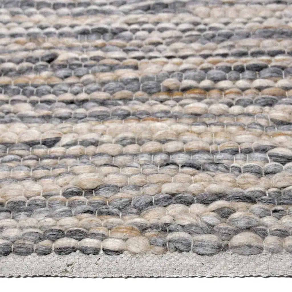 Zijkant detail aanzicht van het vloerkleed MAVIK in de kleuren Grijs / Bruin, gemaakt van 100% Wol.