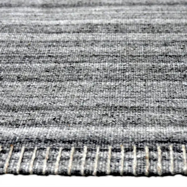 Zijkant detail aanzicht van het vloerkleed PRAVEN STITCH in de kleur Licht Grijs, gemaakt van Katoen.