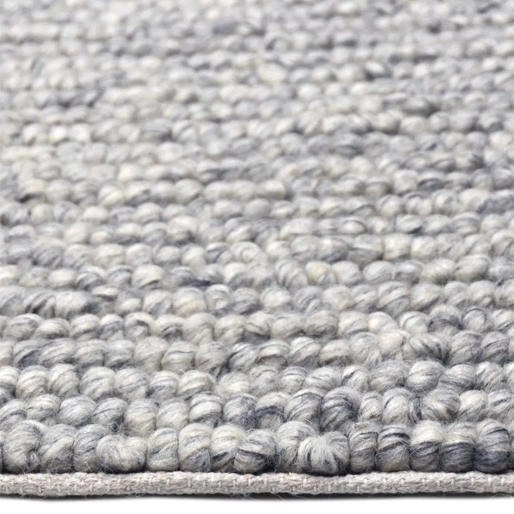 Zijkant detail aanzicht van het vloerkleed SAVONA in de kleur BT Grijs, gemaakt van 100% Wol.