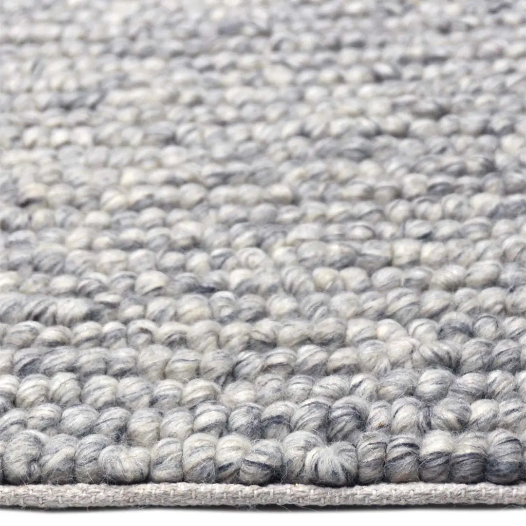 Zijkant detail aanzicht van het vloerkleed SAVONA in de kleur BT Grijs, gemaakt van 100% Wol.